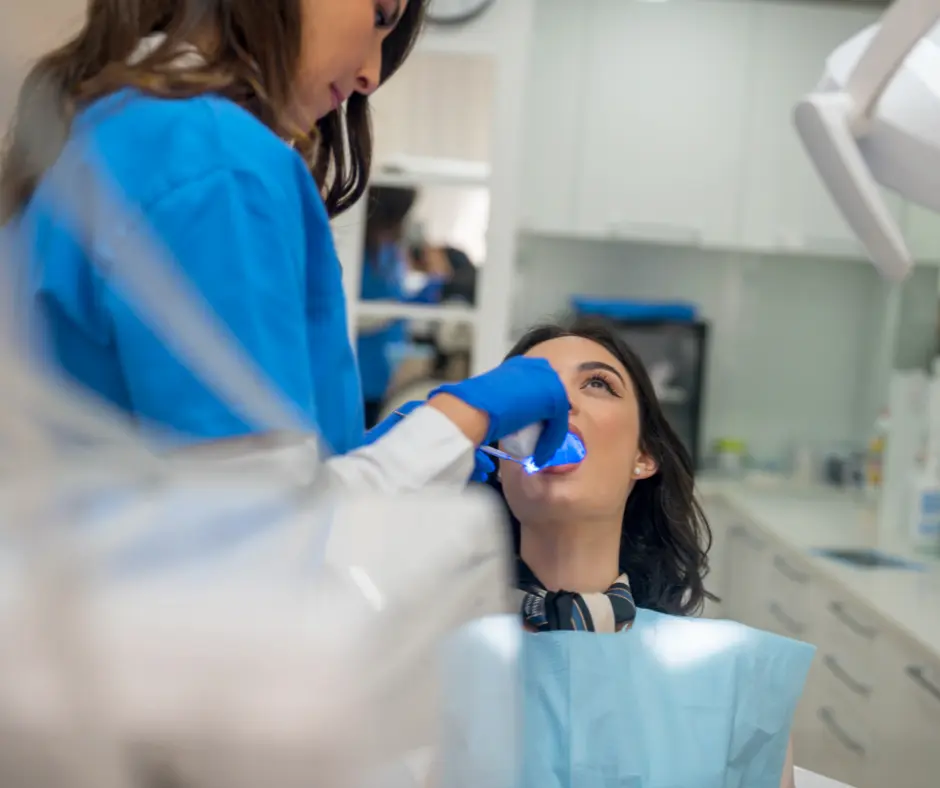 Dental technician cleaning teeth of female patient